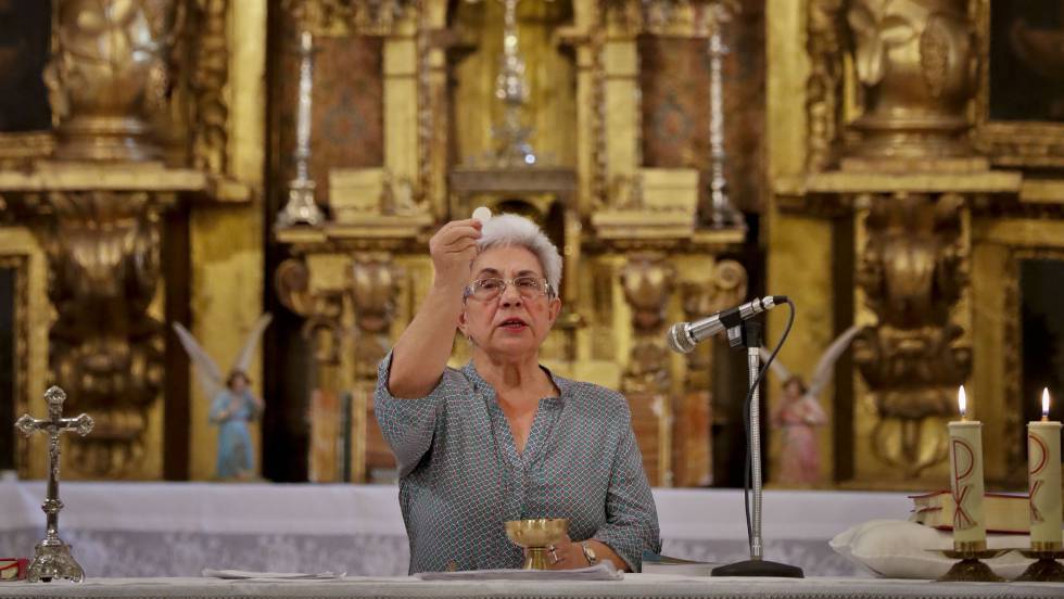 Mujer de avanzada edad consagra la ostia en el altar de un templo católico.