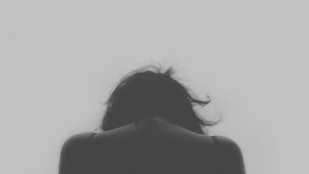 Mujer de espaldas con la cabeza baja.