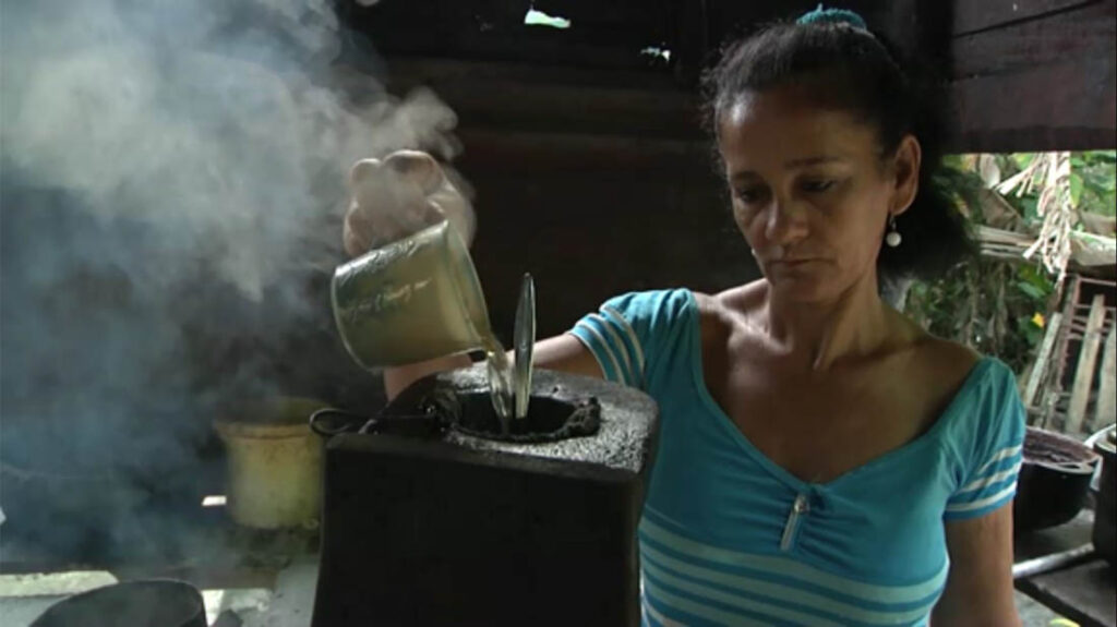Mujer campesina prepara café en condiciones muy rústicas.