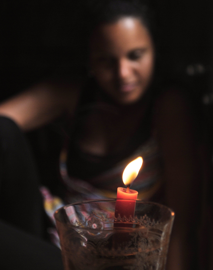 Primer plano de una vela encendida
y detrás una mujer borrosa.