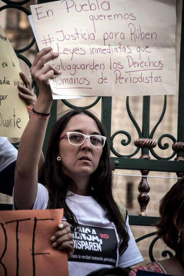 La periodista mexicana Aranzazú Ayala Martínez alzando un cartel con reclamaciones de derechos humanos.