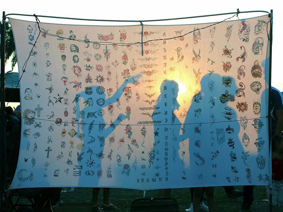 Sábana con muestras de tatuajes, sobre la que se proyectan siluetas de mujeres.