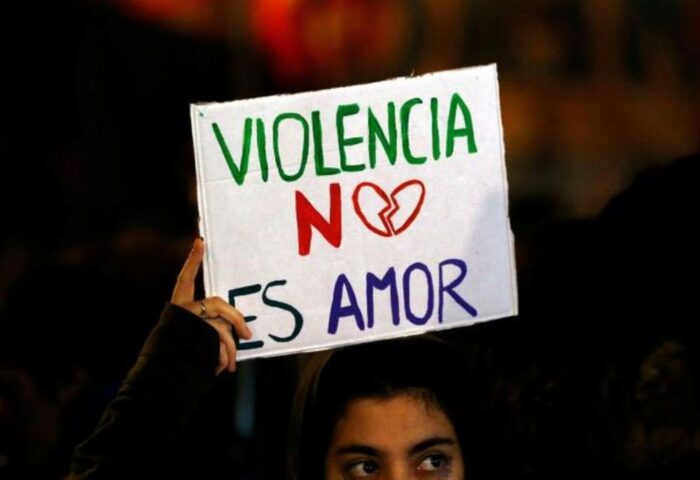 mujer con cartel donde se lee "violencia no es amor"