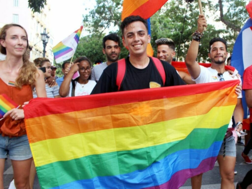 Persona sostiene una bandera del orgulo gay en una manifestación.
