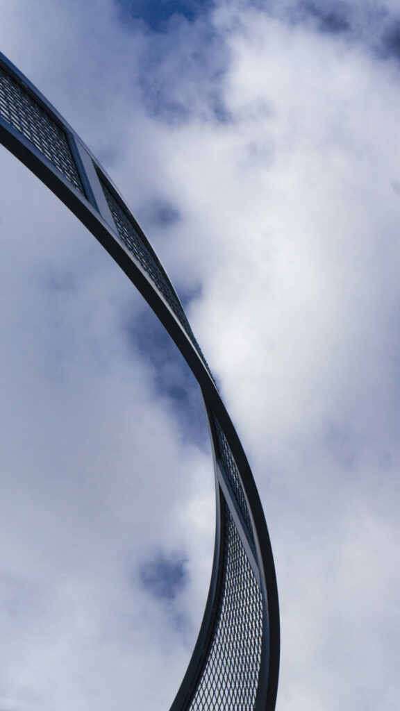 Cielo azul con nubes atravesado por estructura de metal