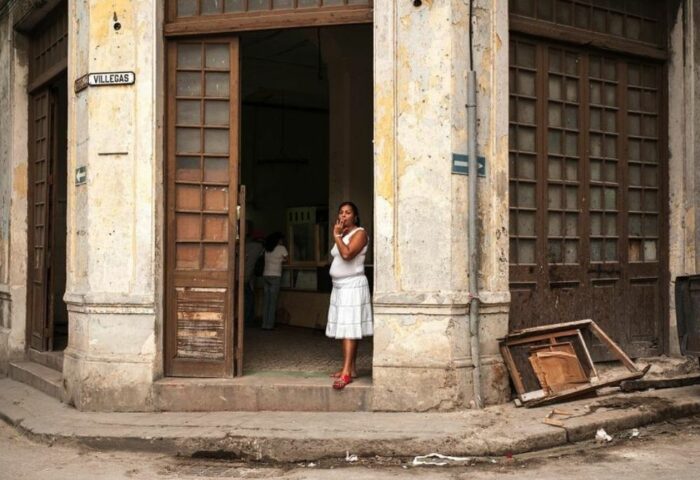 Mujer parada en la puerta de un edificio deteriorado en La Habana.