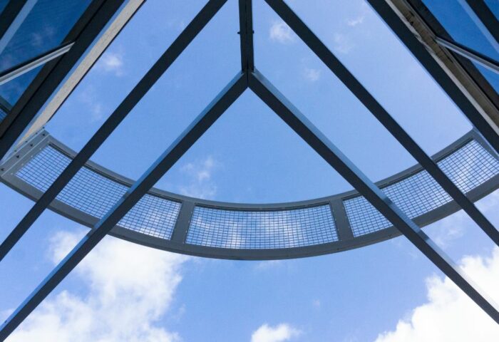 Cielo azul visto a través de rejas y cristales, forma un triángulo que recuerda la forma de una casa.