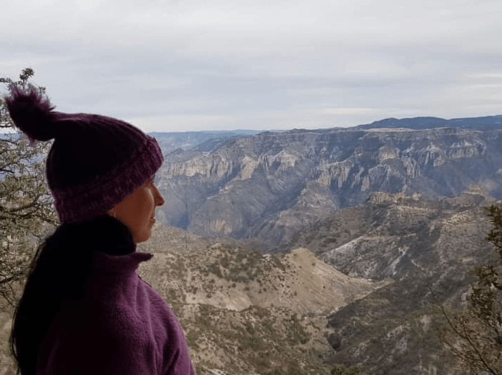 Mujer mirando el horizonte con montañas detrás.