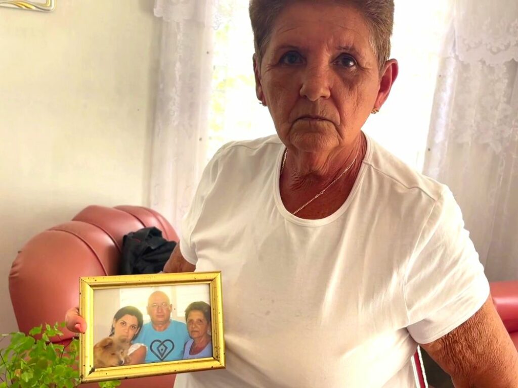 Esposa de preso político sostiene retrato de sus familiares