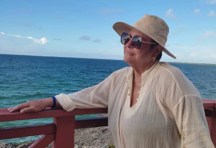 La periodista deportiva cubana Julita Osendi frente al mar, y con sombrero y espejuelos