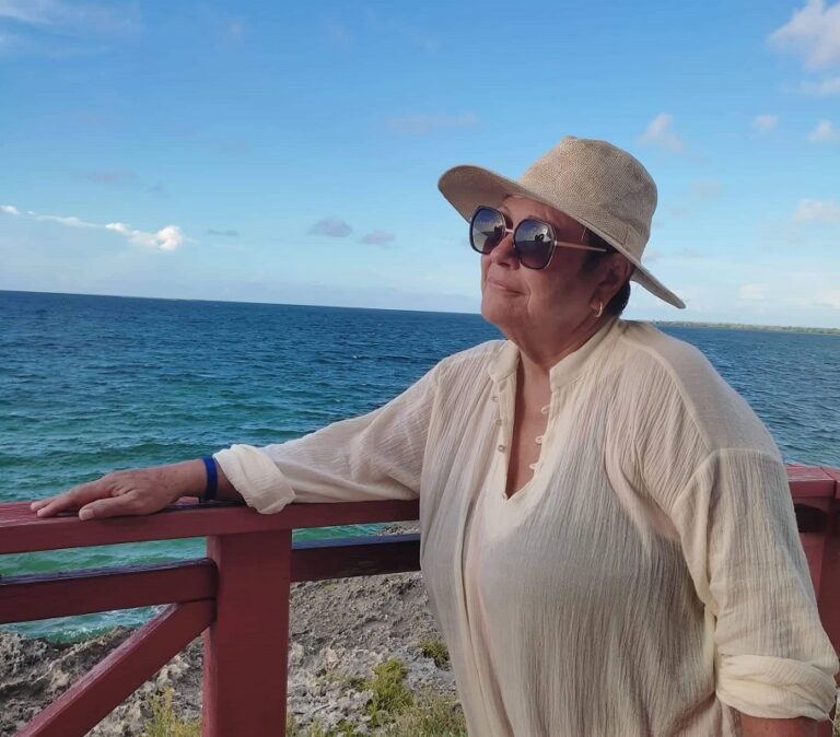La periodista deportiva cubana Julita Osendi frente al mar, y con sombrero y espejuelos