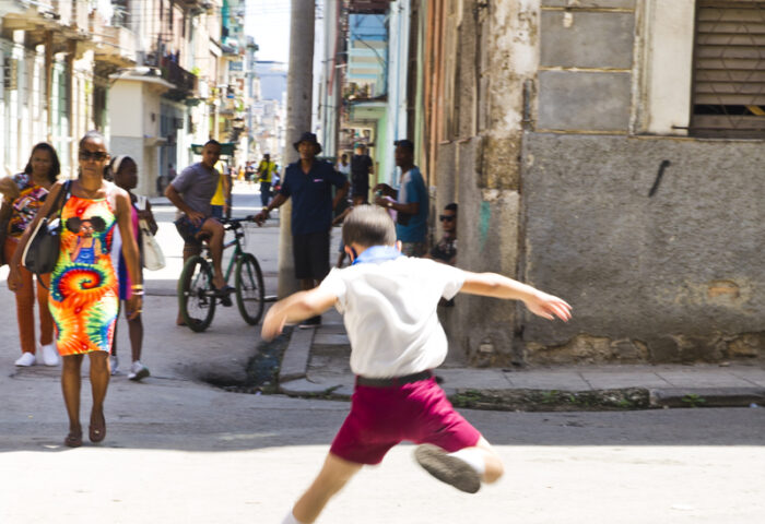 NIño salta sobre charco de agua en la calle.