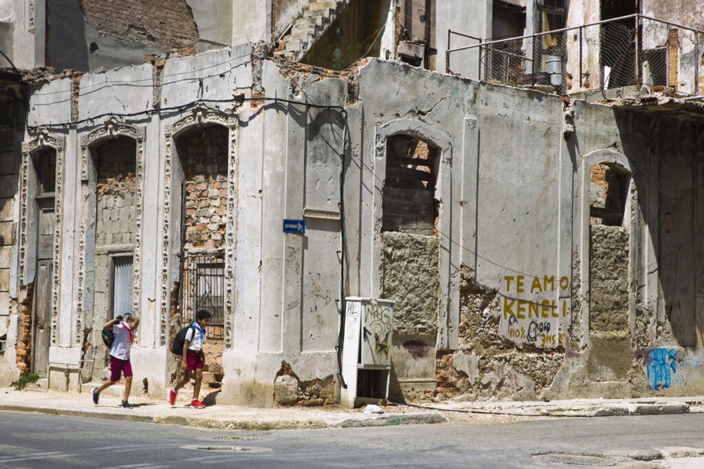 NIños yendo a la escuela entre edificios derrumbados en Cuba.