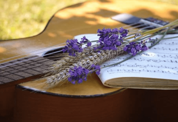Guitarra con flores y la partitura de una canción de amor encima.