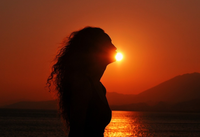 "Runa circular": Mujer de perfil con el sol del atardecer alumbrando su silueta.