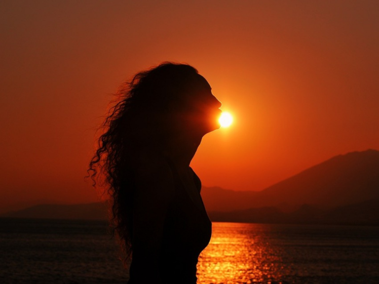 "Runa circular": Mujer de perfil con el sol del atardecer alumbrando su silueta.
