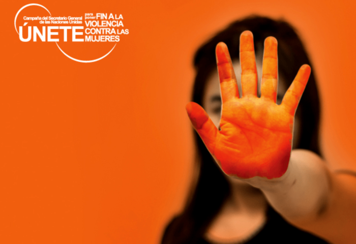 Cartel de “Campaña Únete” contra la violencia machista: Una mujer o niña pone su mano delante (pintada de naranja) en señal de "stop".