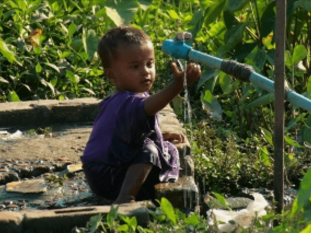 Niño tomando agua en la selva durante la migración masiva a Estados Unidos a través del Tapón del Darién.