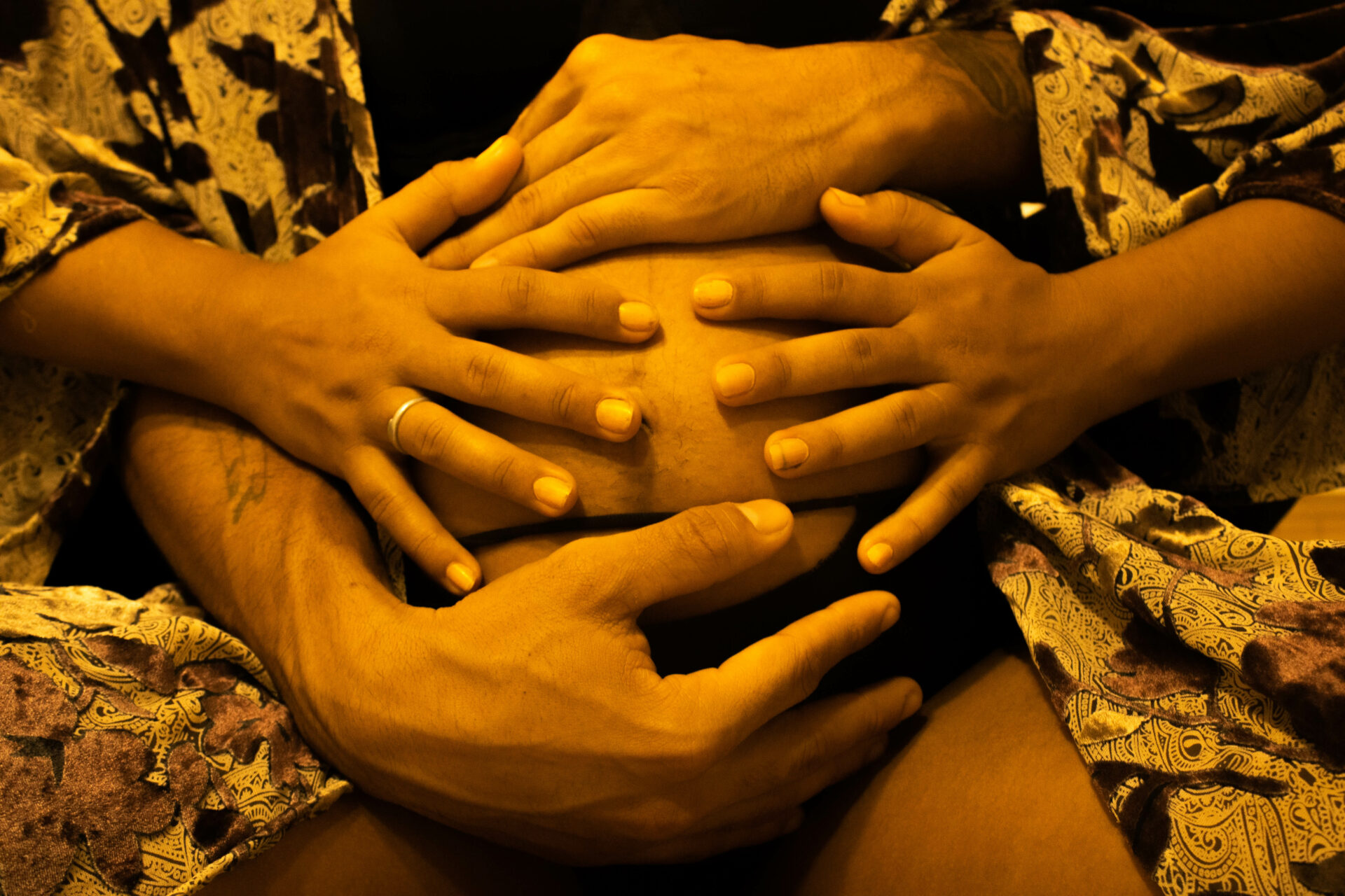 varias manos abrazan la barriga de una mujer embarazada