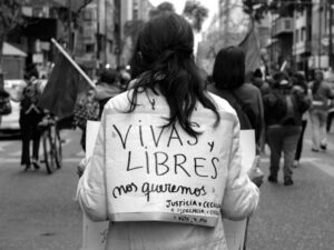 mujer en la calle con un cartel feminista en su espalda