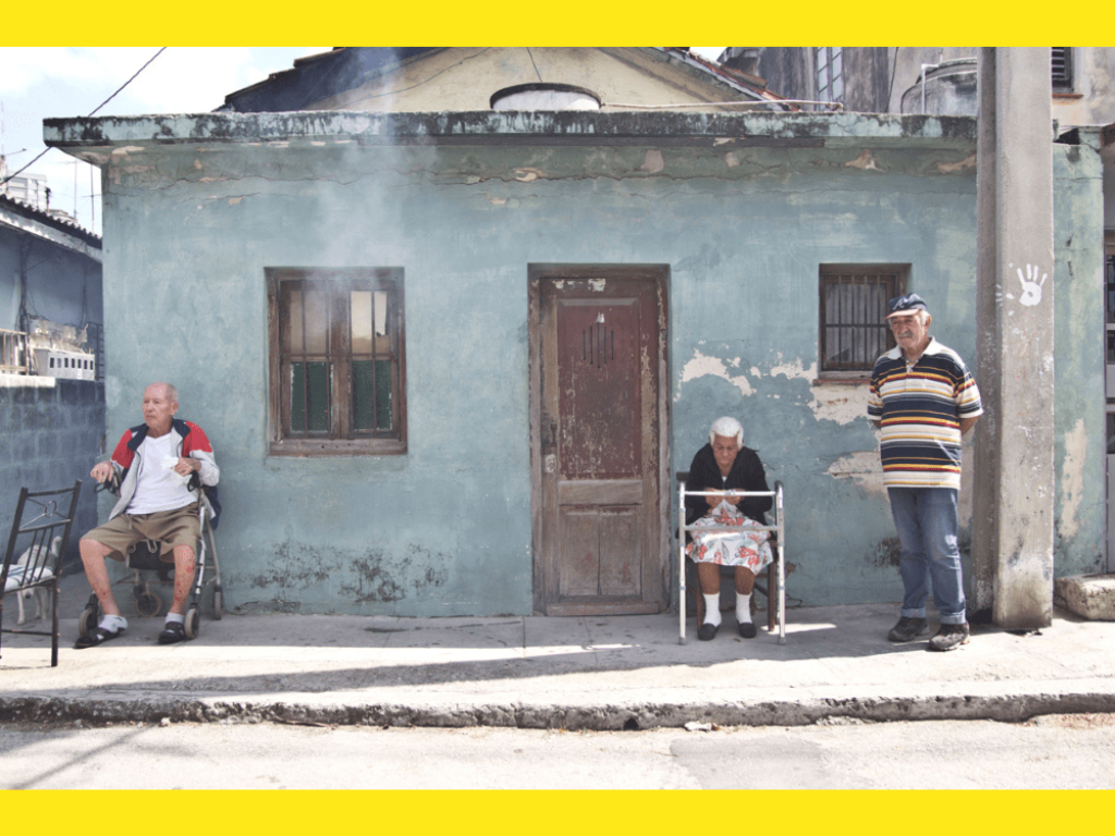 Ancianos esperan sentados en la calle.