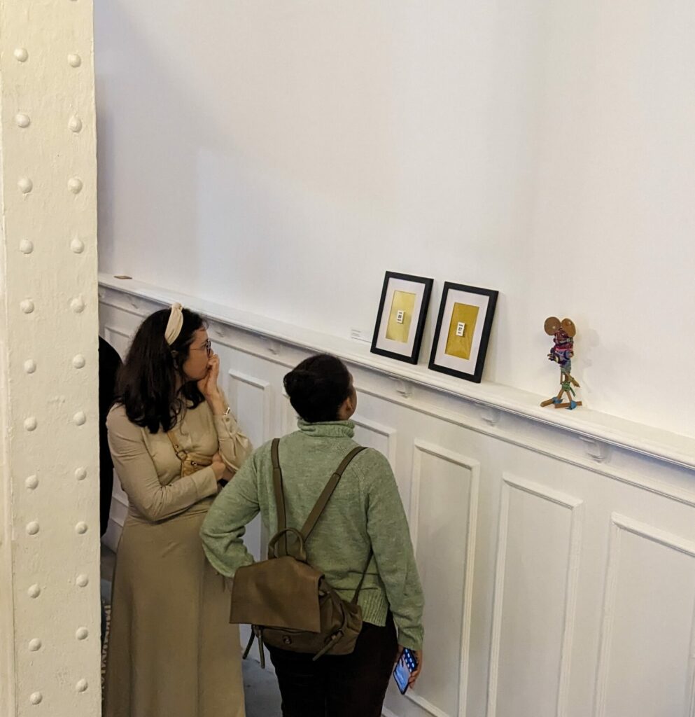 dos personas observan tres obras de arte