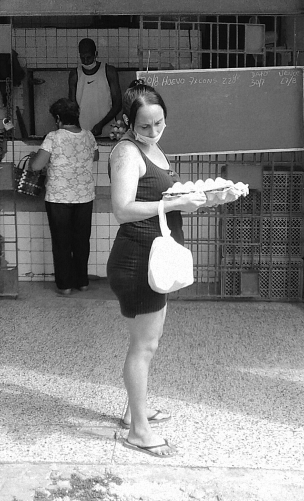 Mujer "haciendo los mandados": lleva una jaba de nylon y un cartón de huevos en las manos.