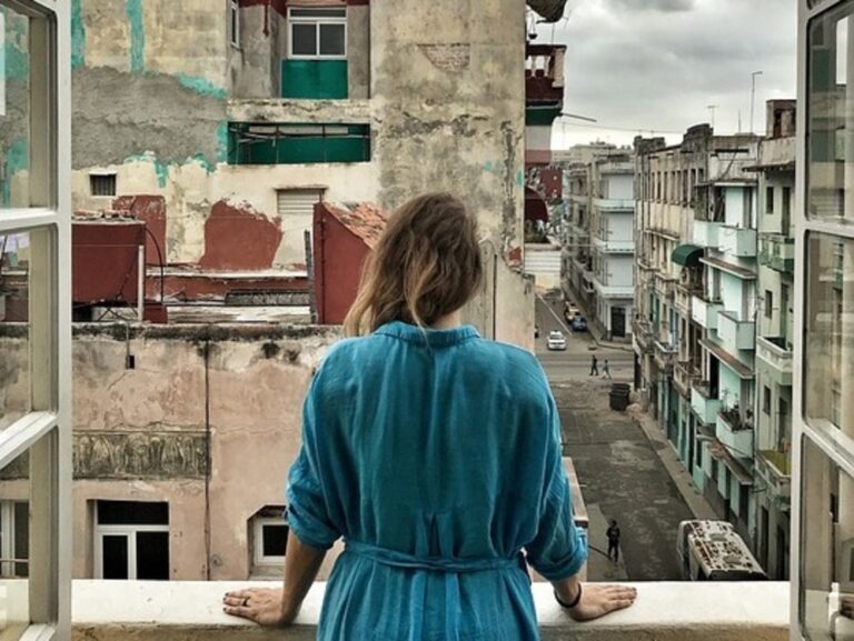 Mujer en un balcón mira la ciudad.