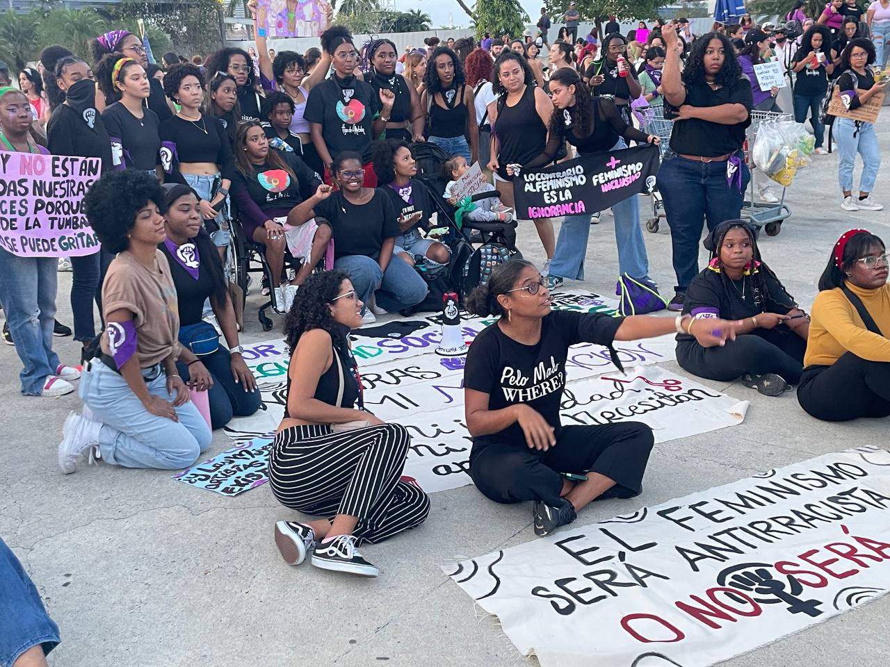Mujeres se reúnen alrededor del cartel El feminismo será antirracista o no será