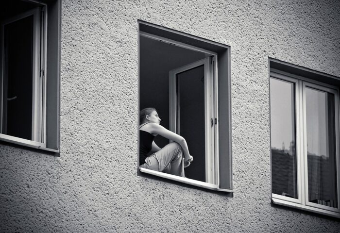 Mujer sentada en la ventana de su casa.