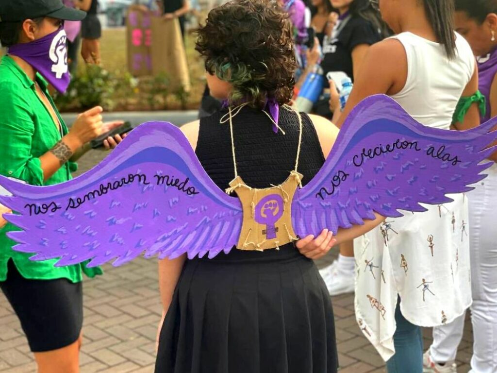 Mujer en manifestación feminista con unas alas a la espalda