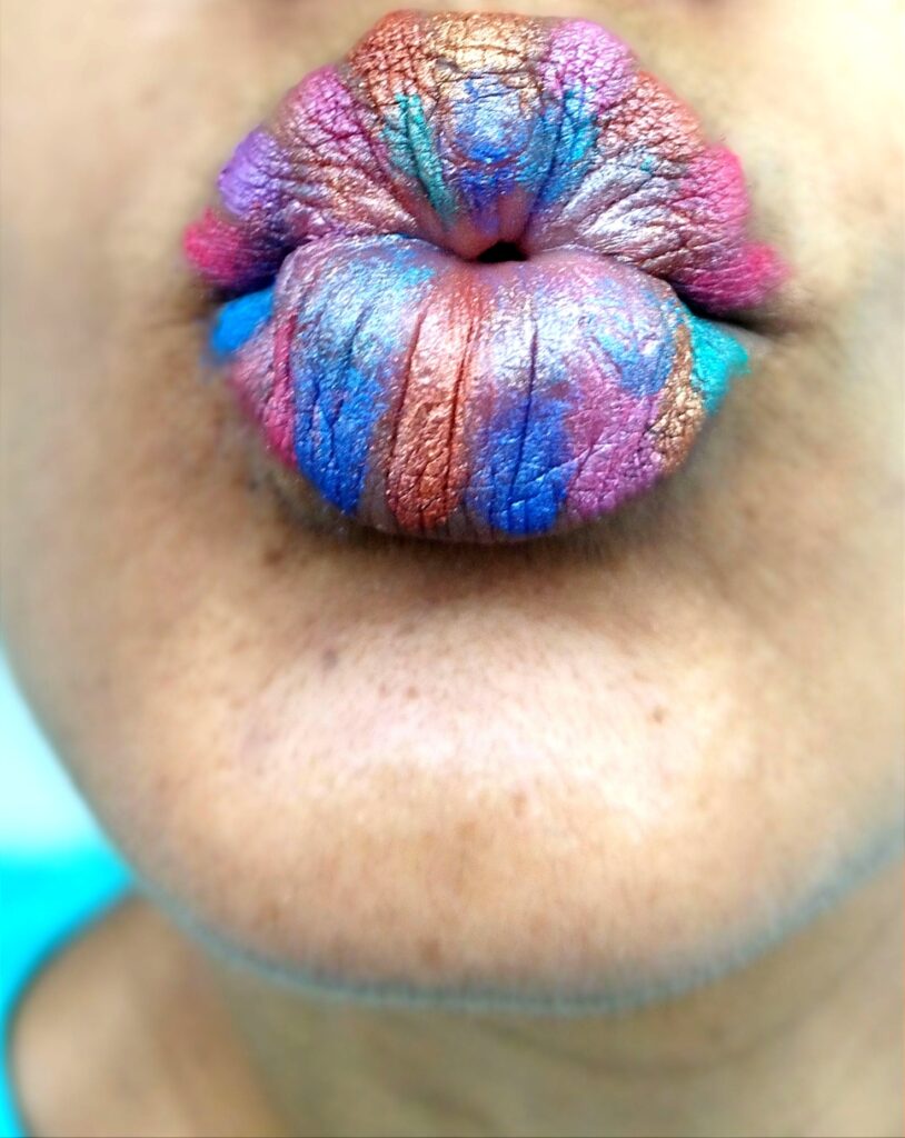 Labios gruesos en forma de beso, con maquillaje de fantasía en azul y rosado.