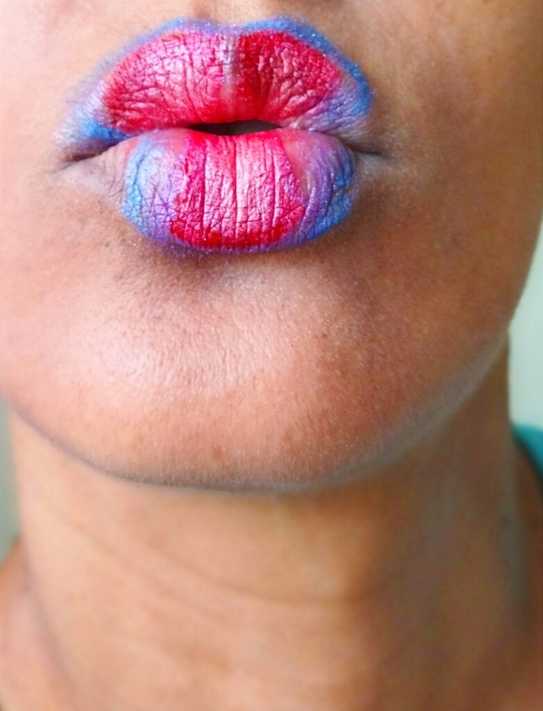 Labios en forma de beso con maquillaje azul y rosa.