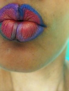 Labios rosa, en forma de mariposa, fileteados en azul.