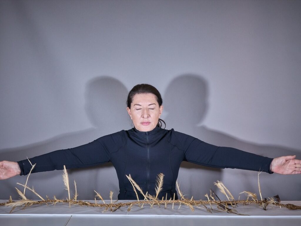 Fotograma del video "The Witch Ladder": Marina Abramović vestida de negro, con los brazos abiertos ante una mesa llena de cuchillos.