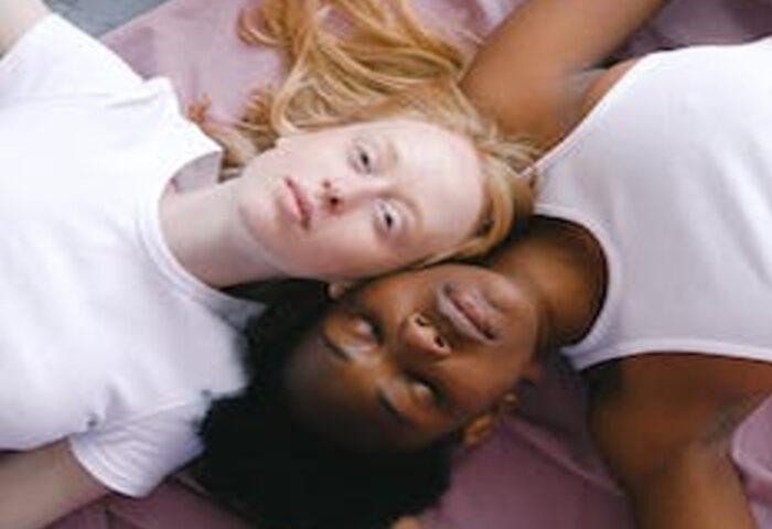 Dos chicas tiradas bocarriba, una es negra y la otra blanca.