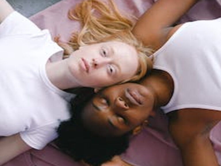 Dos chicas tiradas bocarriba, una es negra y la otra blanca.