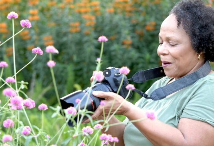 mujer negra, mayor, disfrutando de hacer fotos a la naturaleza como porte de los ecofeminismos