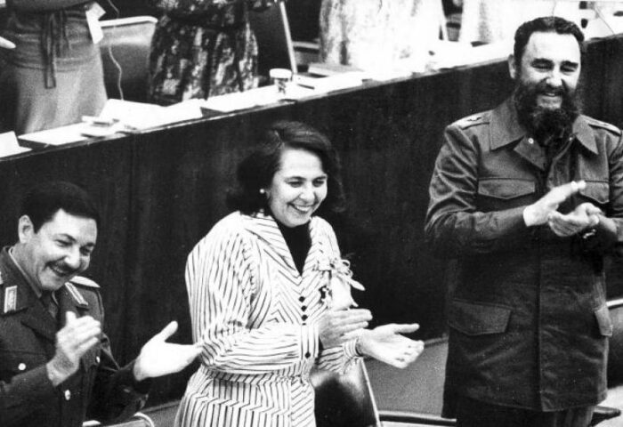 Fotografía donde aparecen Fidel y Raúl Castro, con Vilma Espín al centro, de pie, aplaudiendo.