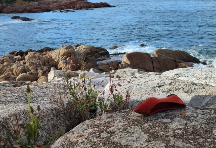 foto de zapato tirado sobre roca frente al mar