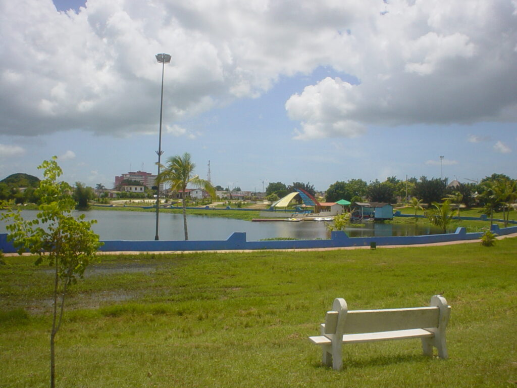 Fotografía del parque recreativo La Turbina, en Ciego de Ávila. Cuba. Se ve el lago desde el césped con un banco para descansar y observar la laguna de la que se dice que puede habitar una madre de aguas.