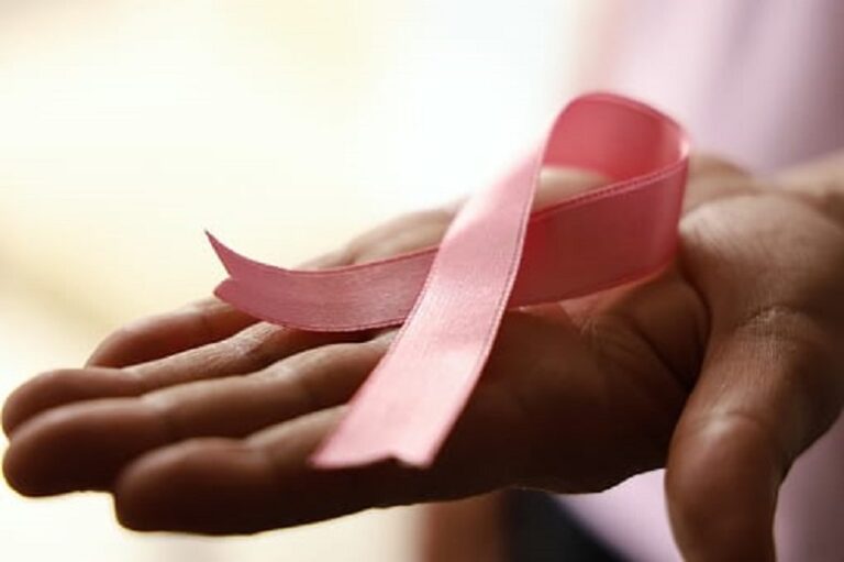 foto de una mano extendida con el lazo símbolo de la lucha contra el cáncer de mama.