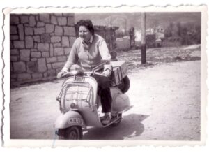 La poeta Gloria Fuertes montada en una moto vespa.