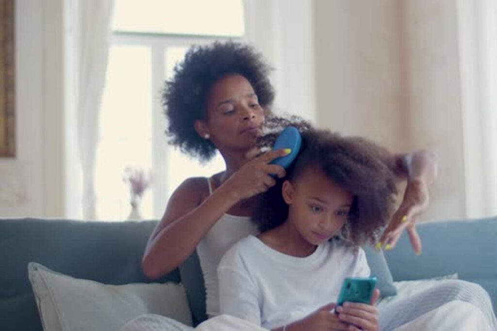madre peinando a niña de pelo afro.