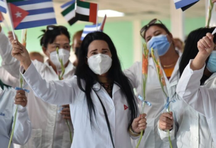 Mujeres en misión médica cubana hondeando banderas.