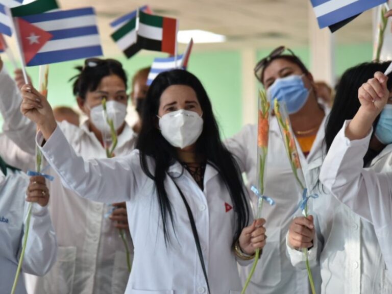 Mujeres en misión médica cubana hondeando banderas.