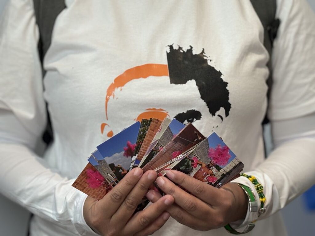 Yanelys Nuñez sosteniendo postales de Miss Bienal