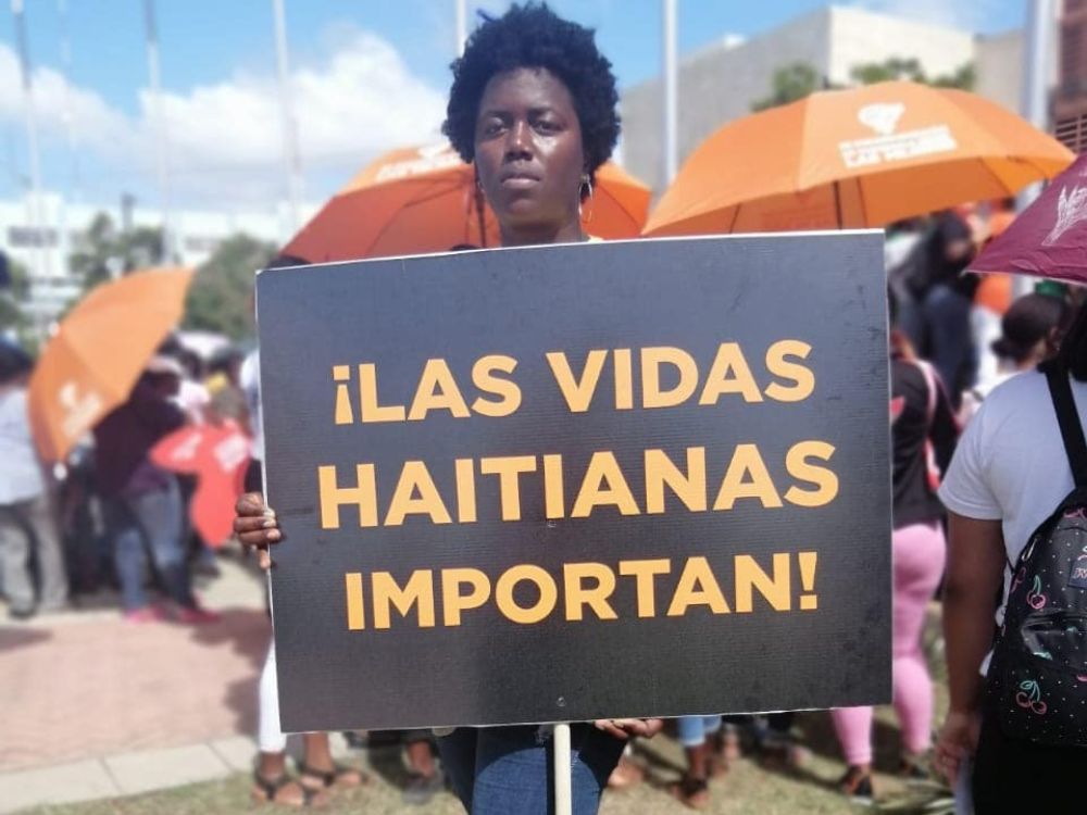 Mujer con cartel sobre las vidas haitianas