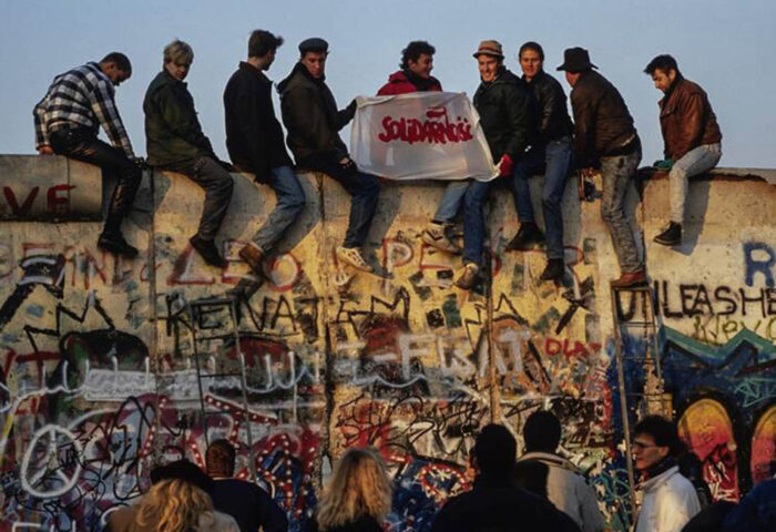 Jóvenes alemanes del este y el oeste sostienen un cartel de Solidarność sobre el Muro de Berlín. Foto: Lothar M. Peter