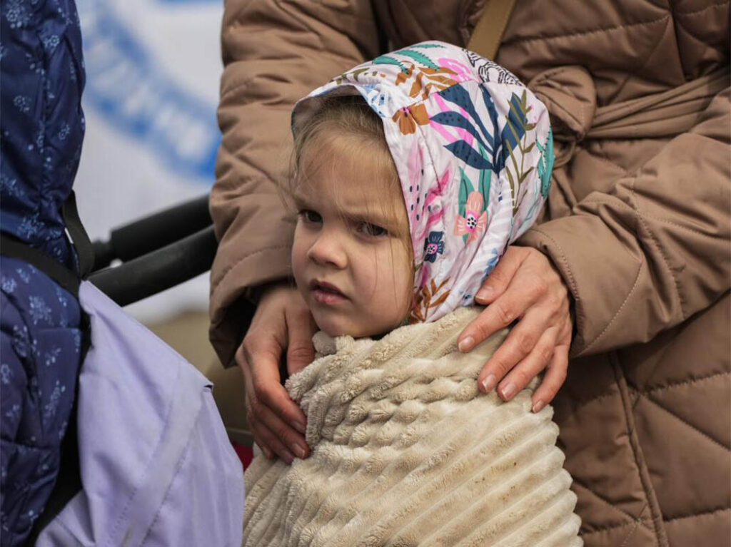 Niña ucraniana desplazada por la guerra espera en un cruce fronterizo con Polonia, abril de 2022. Foto: Sergei Grits
